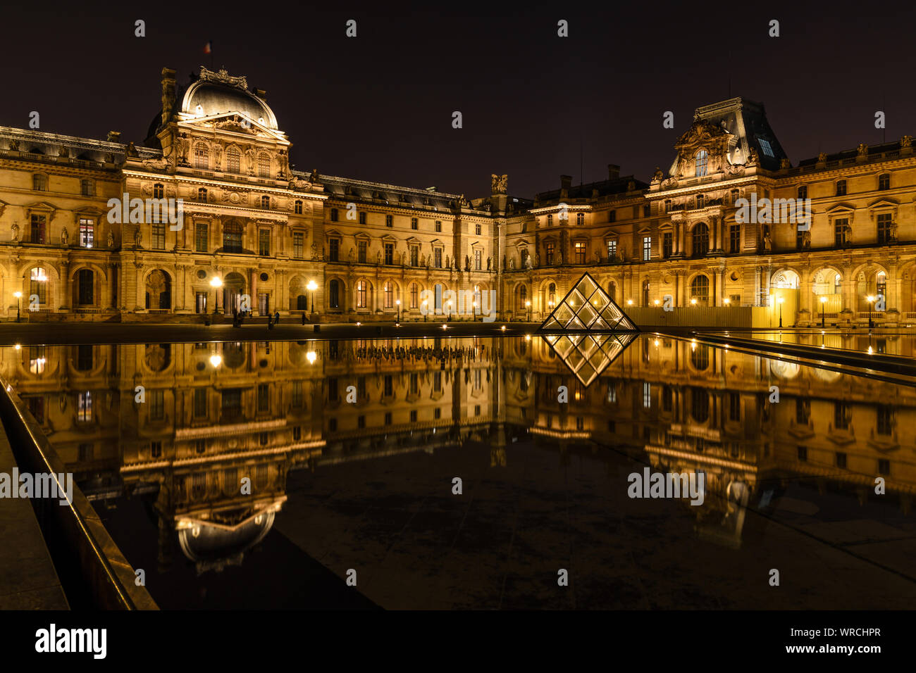 PARIS, FRANCE - DECEMBER 3, 2013: Night view of the Louvre Museum reflected on the water of a basin. Stock Photo