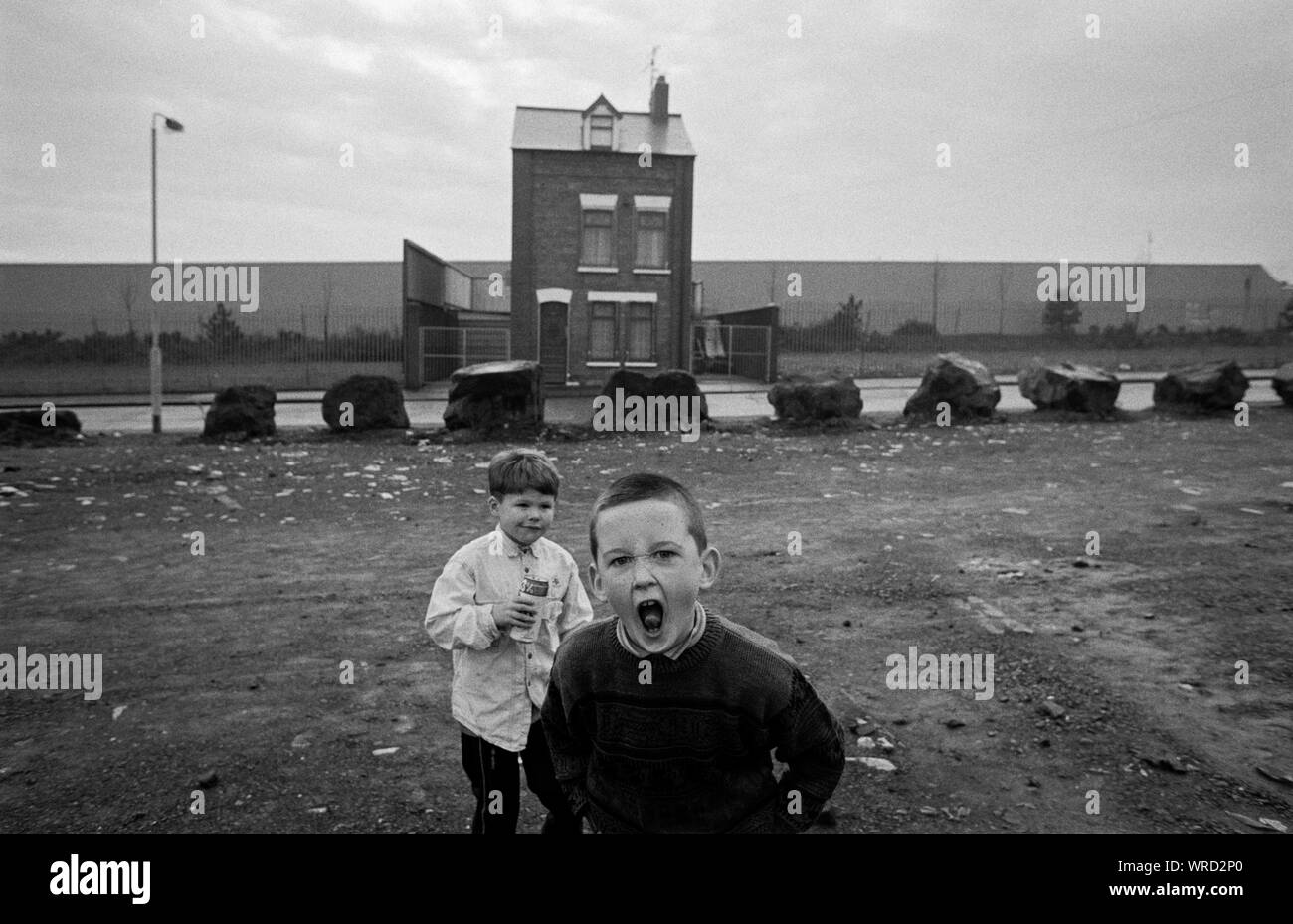 Children play in front of a solitary house, which is surrounded by a 'peace wall', in Roe Street, North Belfast, Northern Ireland, in December 1992. Stock Photo