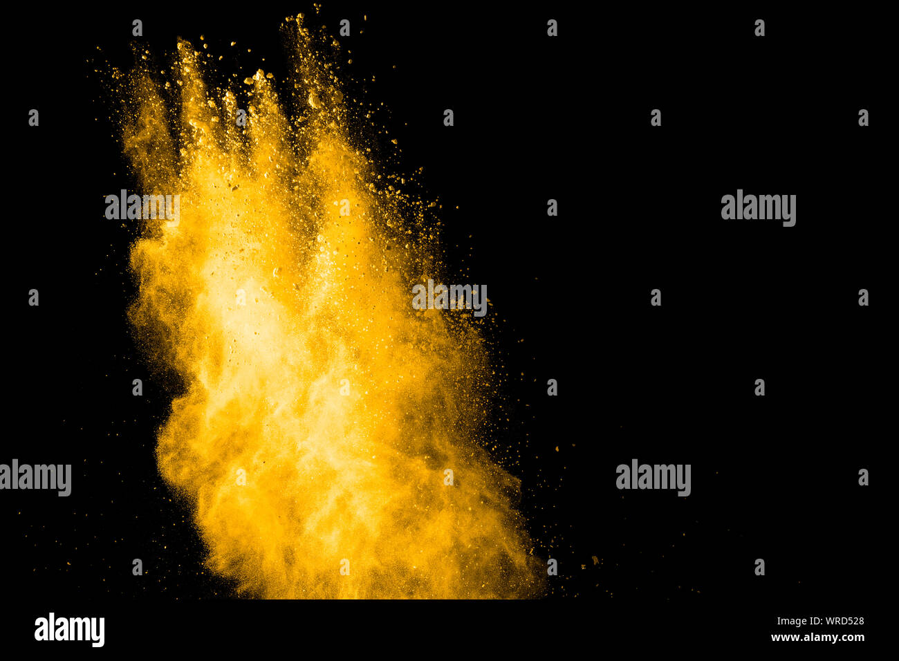 Yellow dust particles explosion on black background.Yellow powder dust