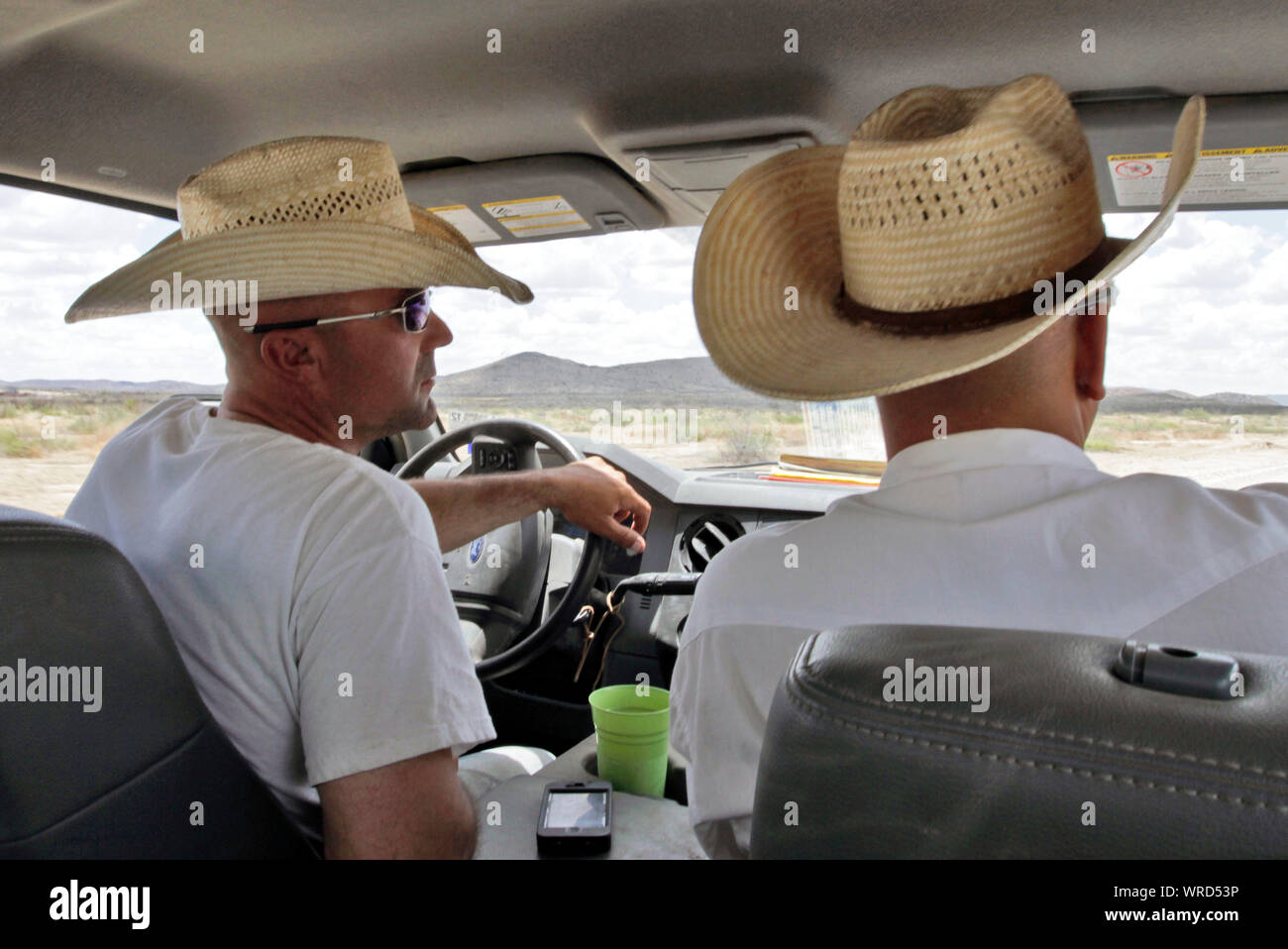 Cowboys driving on a West Texas ranch at the end of a workday. Stock Photo