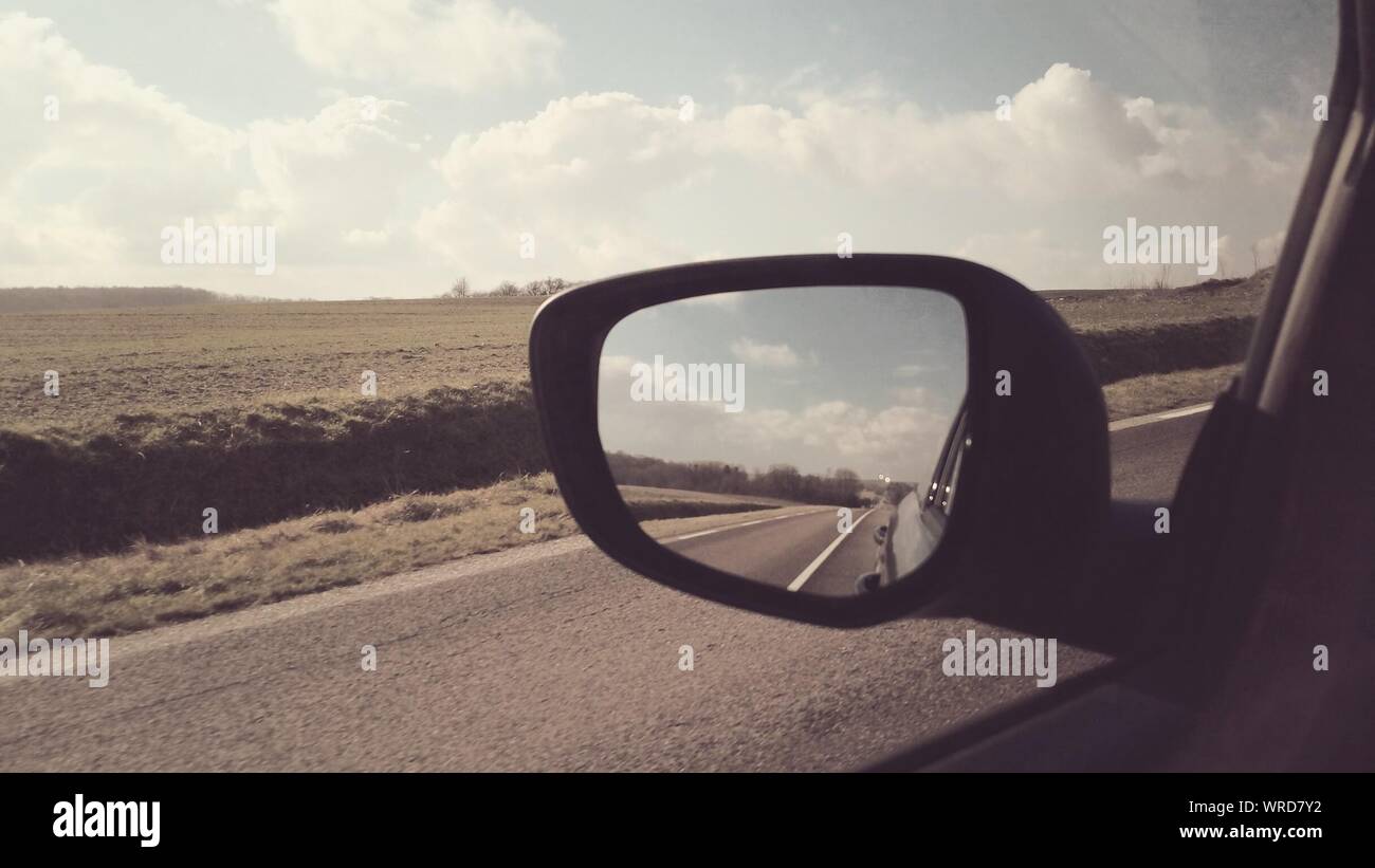 View Of Side-view Mirror Against Sky Stock Photo