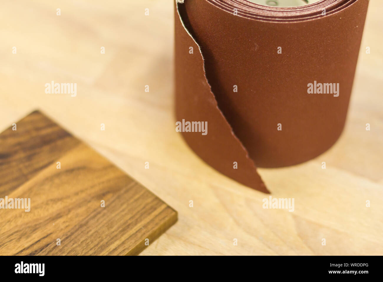 Woodworking Sandpaper Roll on workbench Preparation with walnut woodwork Stock Photo