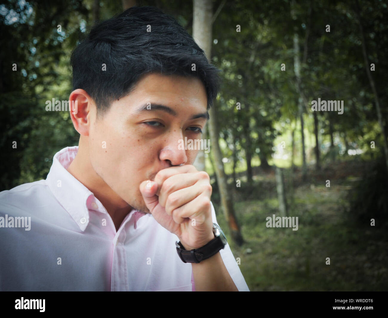 Man Coughing Against Trees At Forest Stock Photo