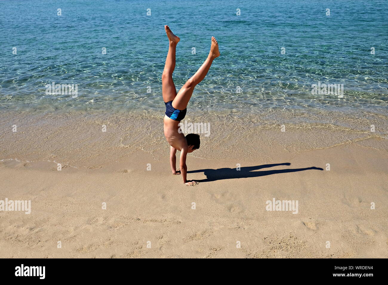 boy does handstand on the beach Stock Photo