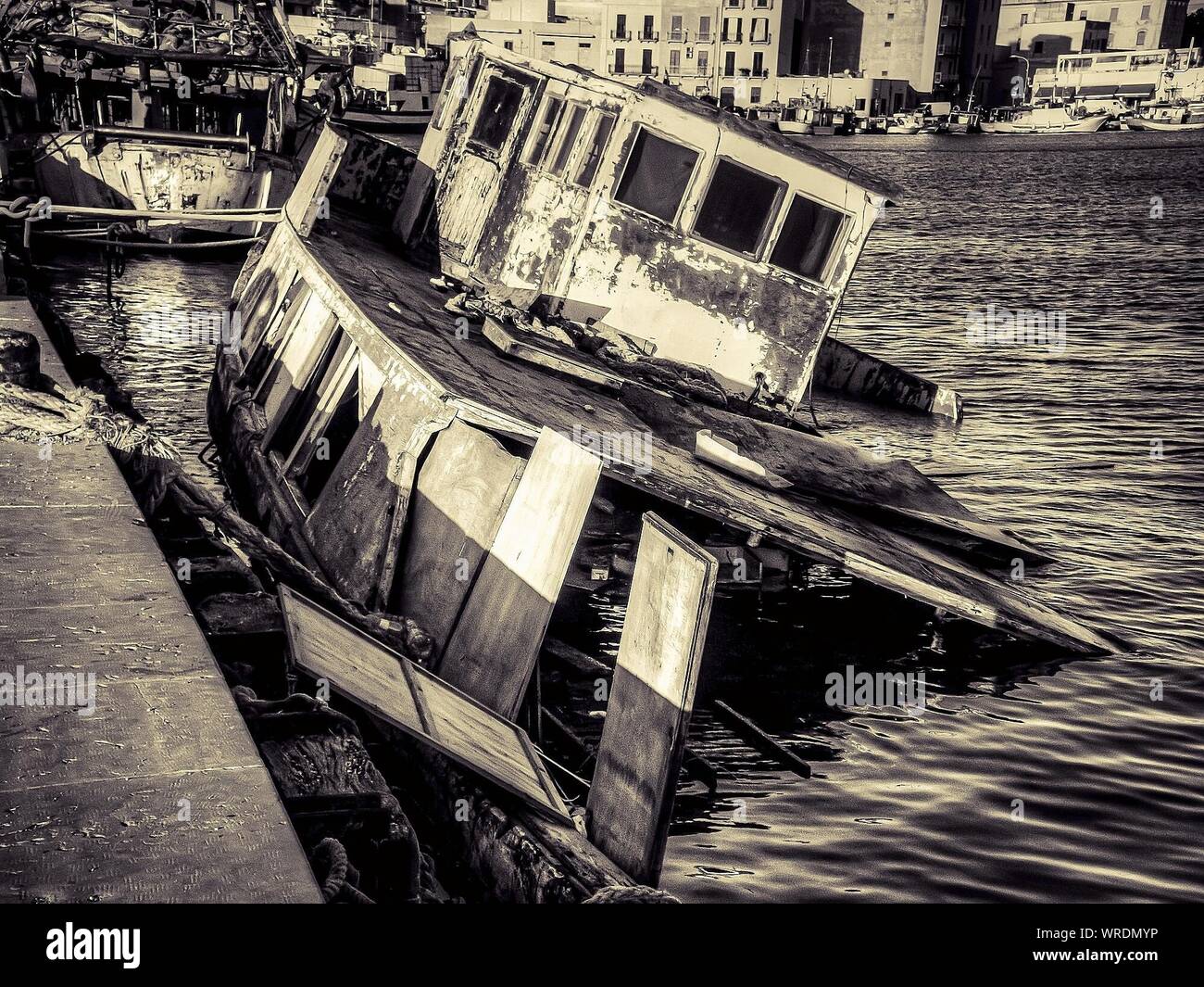 Abandoned Damaged Boat Sinking At Harbor Stock Photo