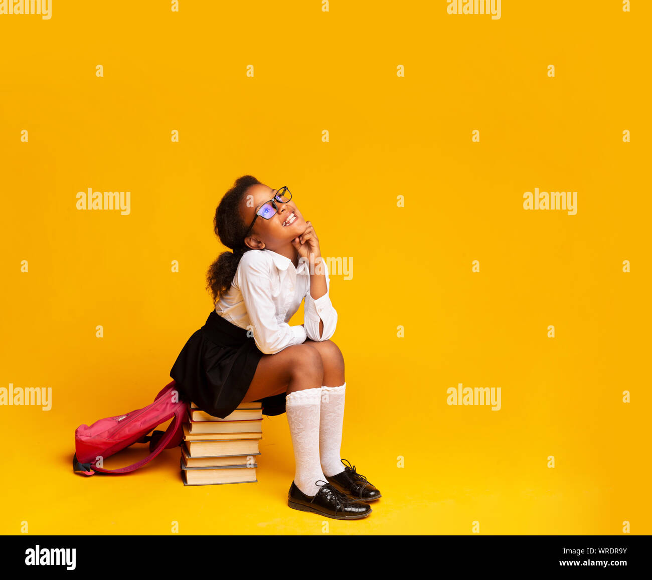 Elementary School Girl Dreaming Sitting On Stack Of Books Stock Photo ...