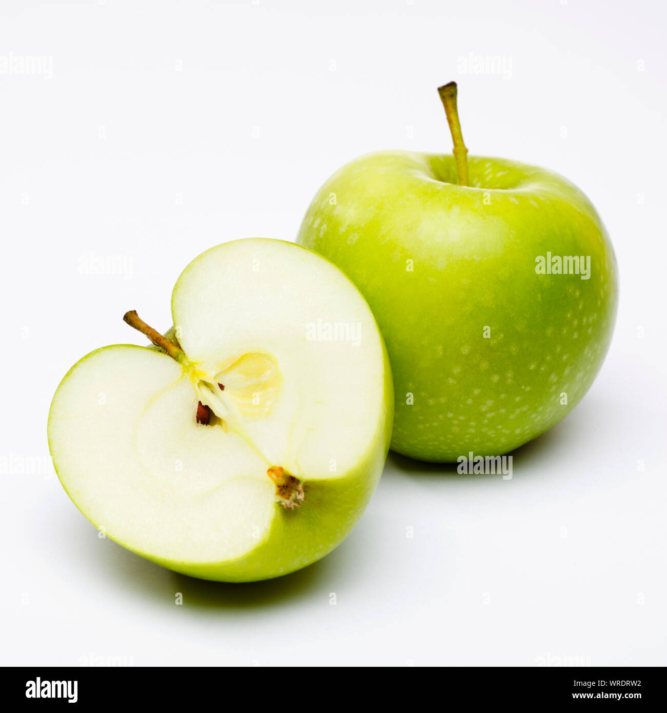 Apples, whole and one green apple sliced in half on a white background Stock Photo