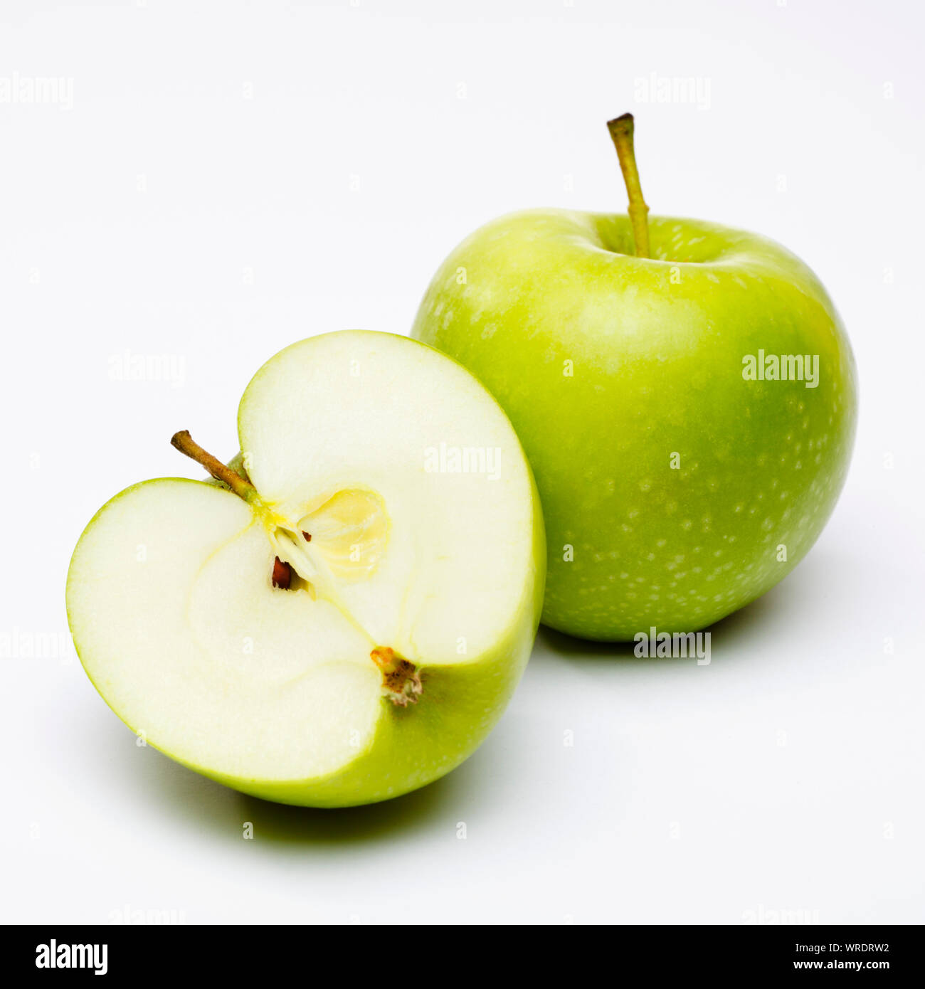 Green apples, whole and sliced in half on a white background Stock Photo