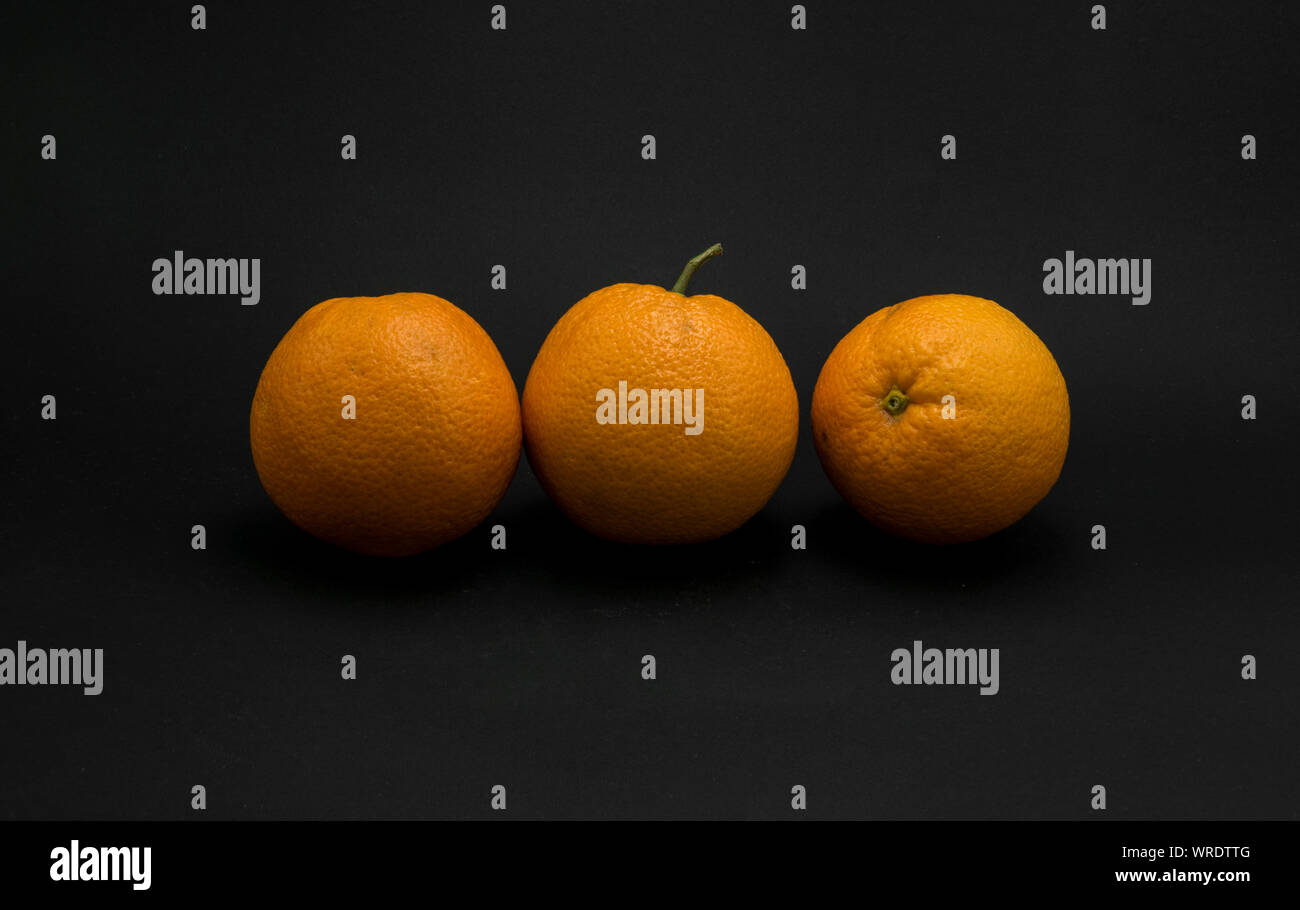 Three fresh oranges on black background. Stock Photo