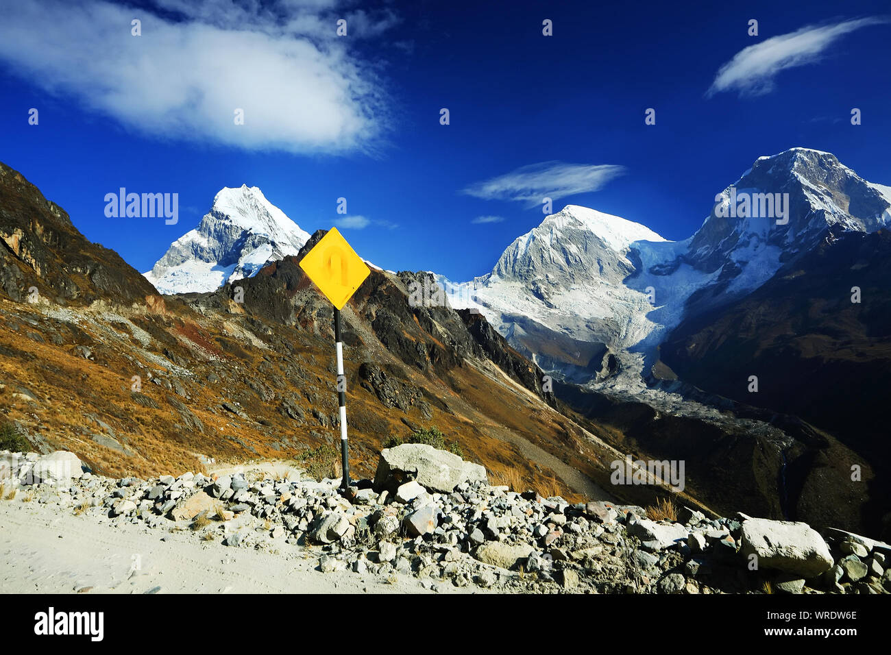 Yellow Sign Post By Stones With Mountain Peak In Background Stock Photo