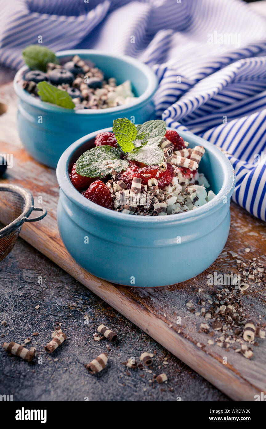 Vertical shot cottage dessert with jam in blue deep bowl, Strawberry jam and blueberries Stock Photo