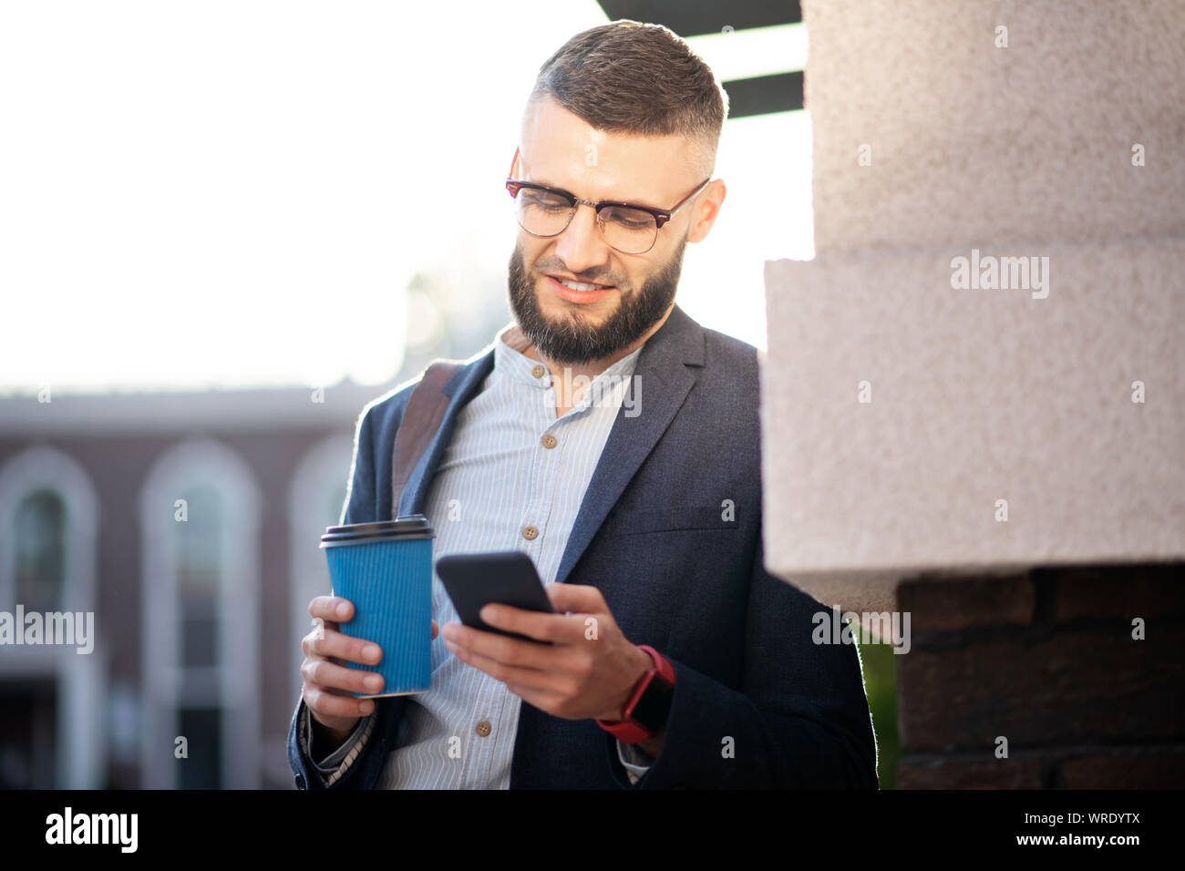 Businessman enjoying break outside reading messages on phone Stock Photo