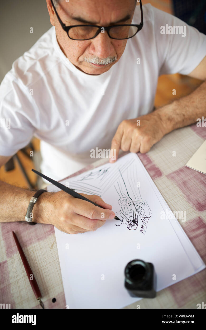 Senior man drawing with pen. Stock Photo