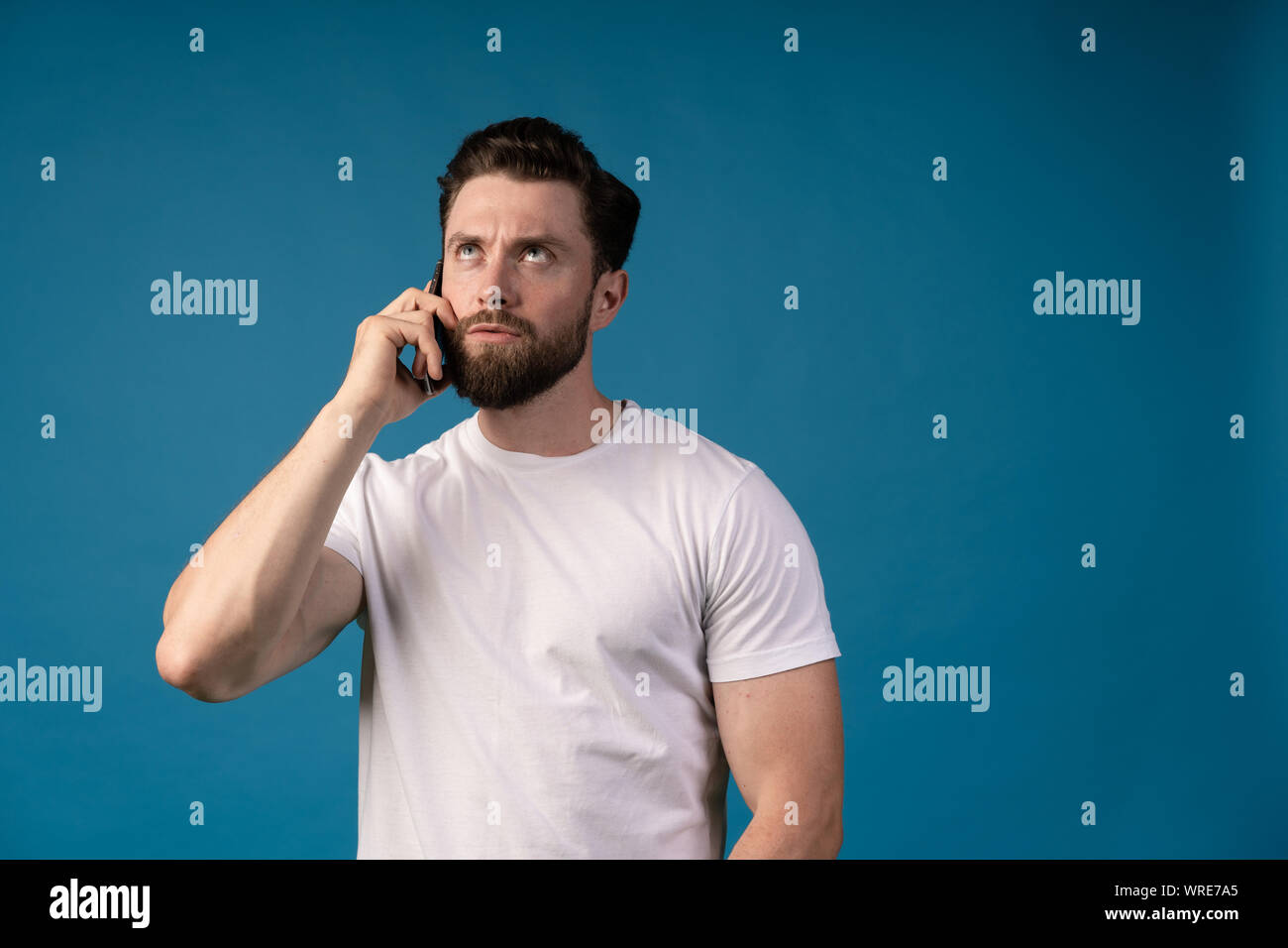 Portrait Of Worried Young Man On The Phone. Pull his eyes up. Feel kinda dissatisfied. Stock Photo