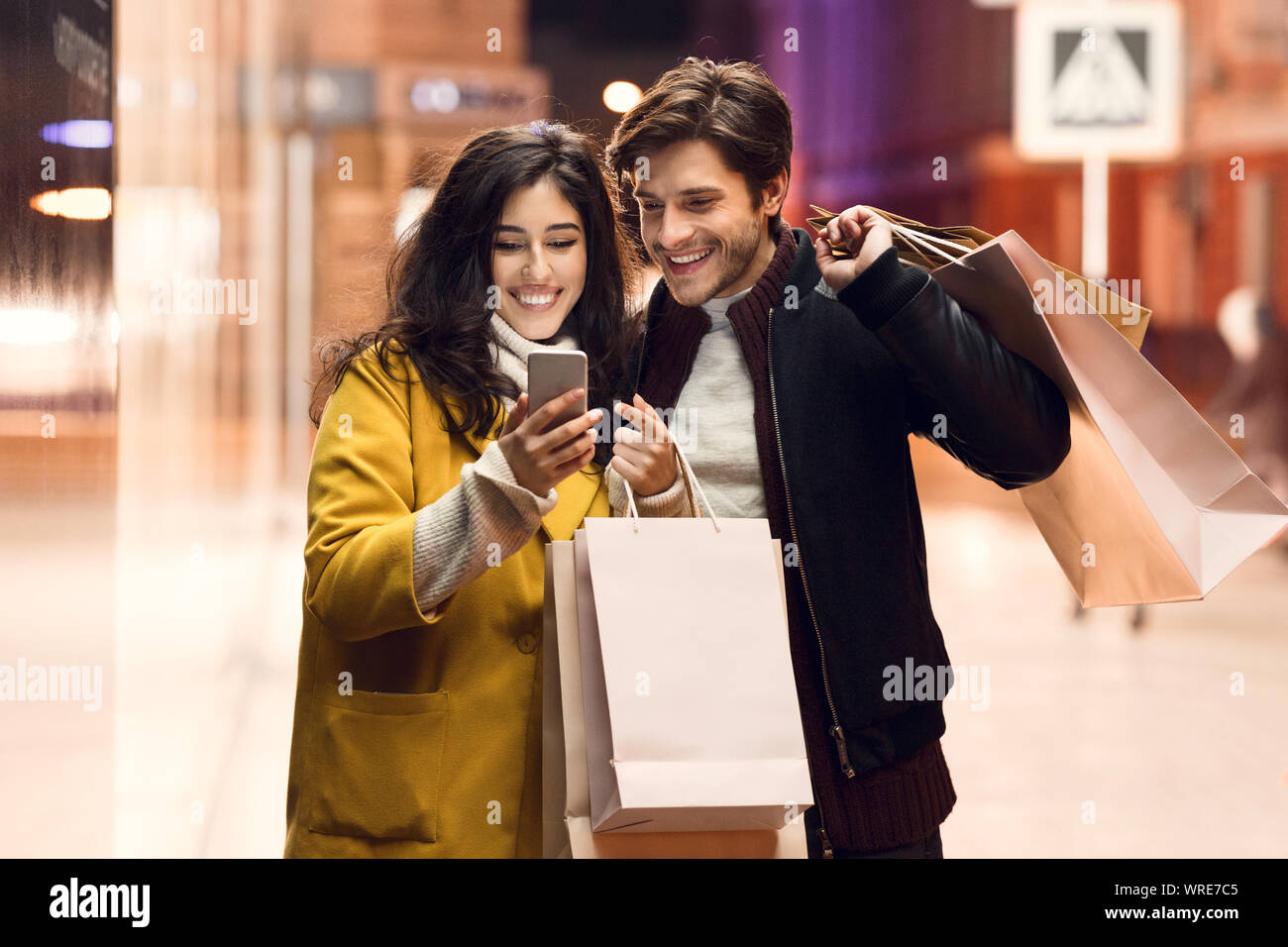 Consumerism concept. Couple with paper bags and smartphone Stock Photo