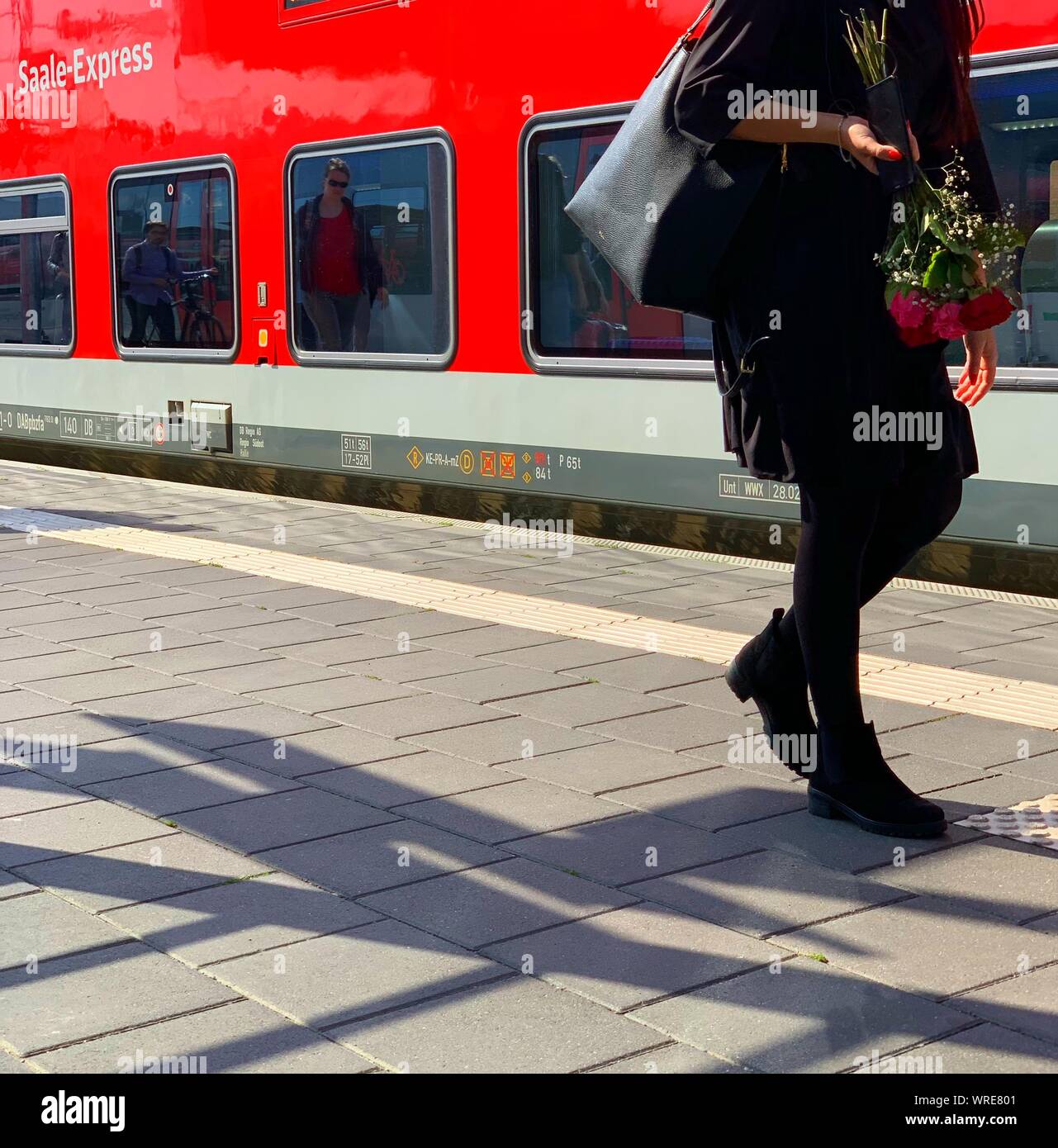 A woman with red roses and mourning clothes walks along a platform in Germany. Stock Photo