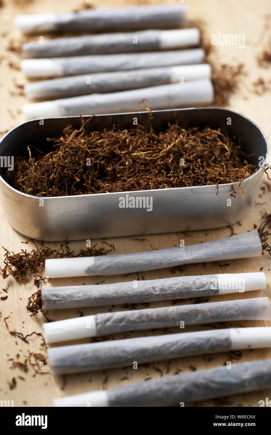 how much are roll up cigarettes Hand rolling tobacco on a wood table Stock Photo