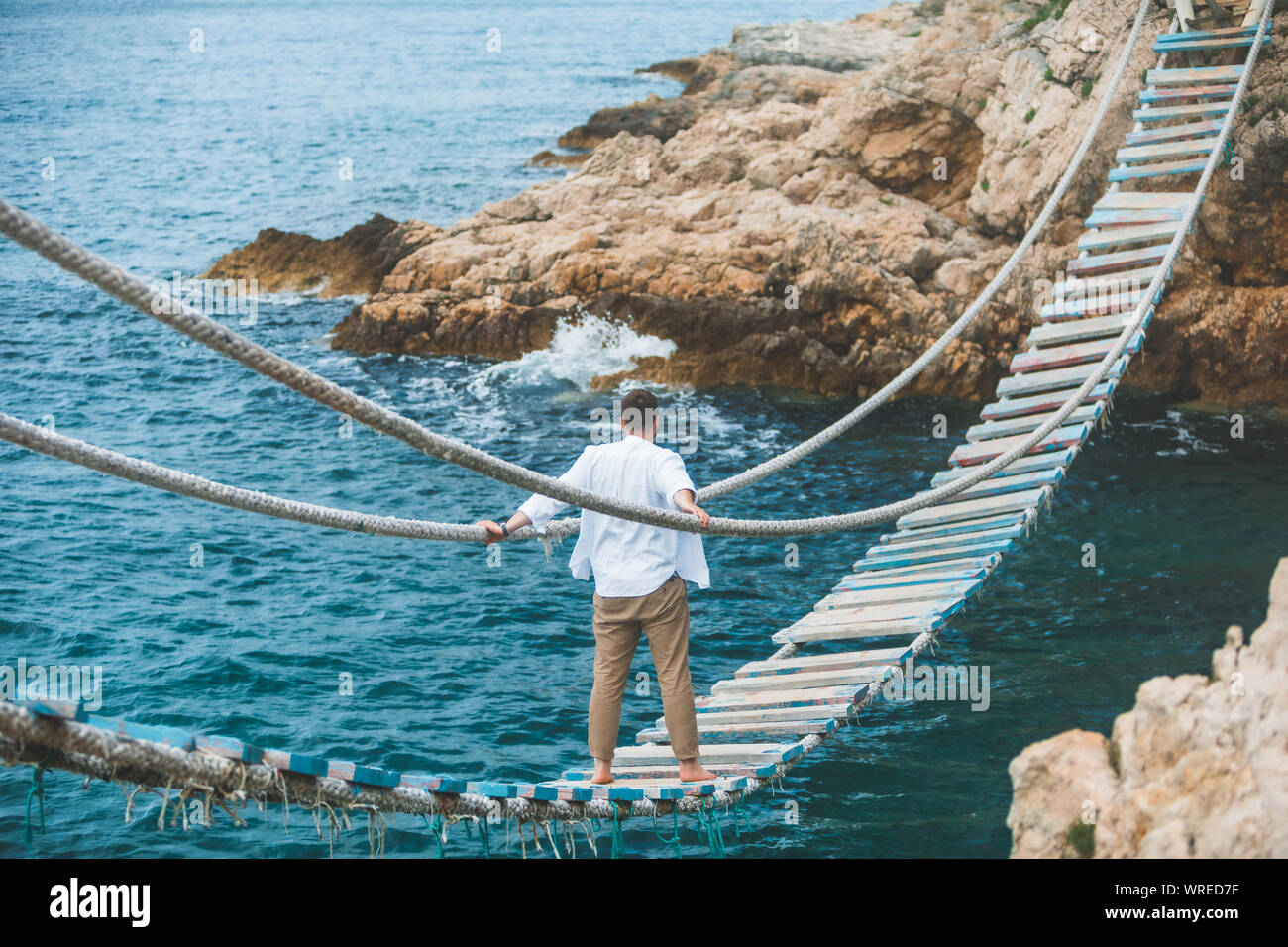man walking by suspension bridge cross sea bay Stock Photo - Alamy