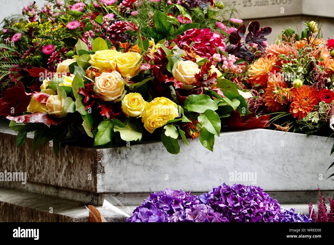 Assorted, brilliantly colored, fresh flowers adorn a grave in Père