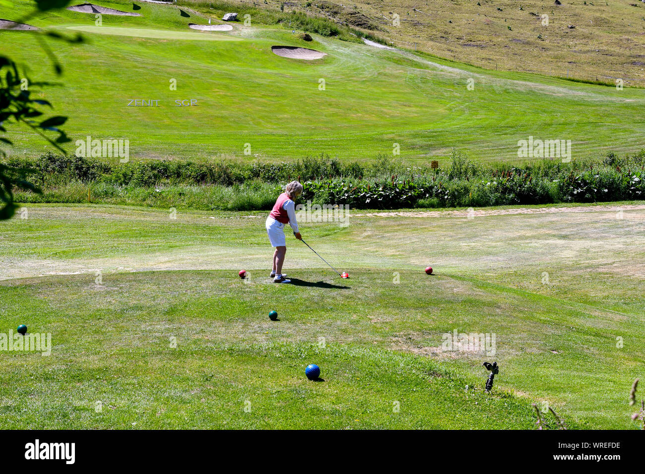 A middle-aged woman playing golf at Golf Club Courmayeur and Grandes Jorasses of Val Ferret, a valley at the foot of Mont Blanc massif, Alps, Italy Stock Photo