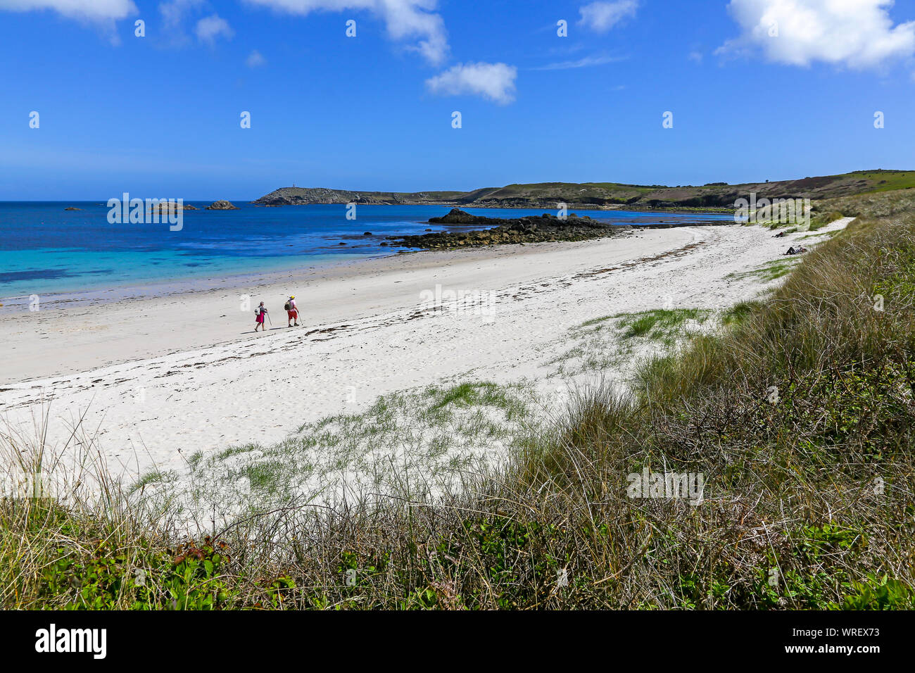 2 people walking on an almost deserted beach at Great Bay in St Martin's Bay, St. Martin’s Island, Isles of Scilly, Cornwall, England, UK Stock Photo