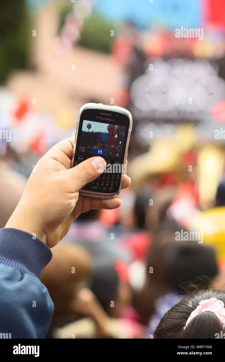 LIMA, PERU - JULY 21, 2013: Unidentified person holding a Blackberry mobile phone to take a photo on the Wong Parade in Miraflores on July 21, 2013 Stock Photo