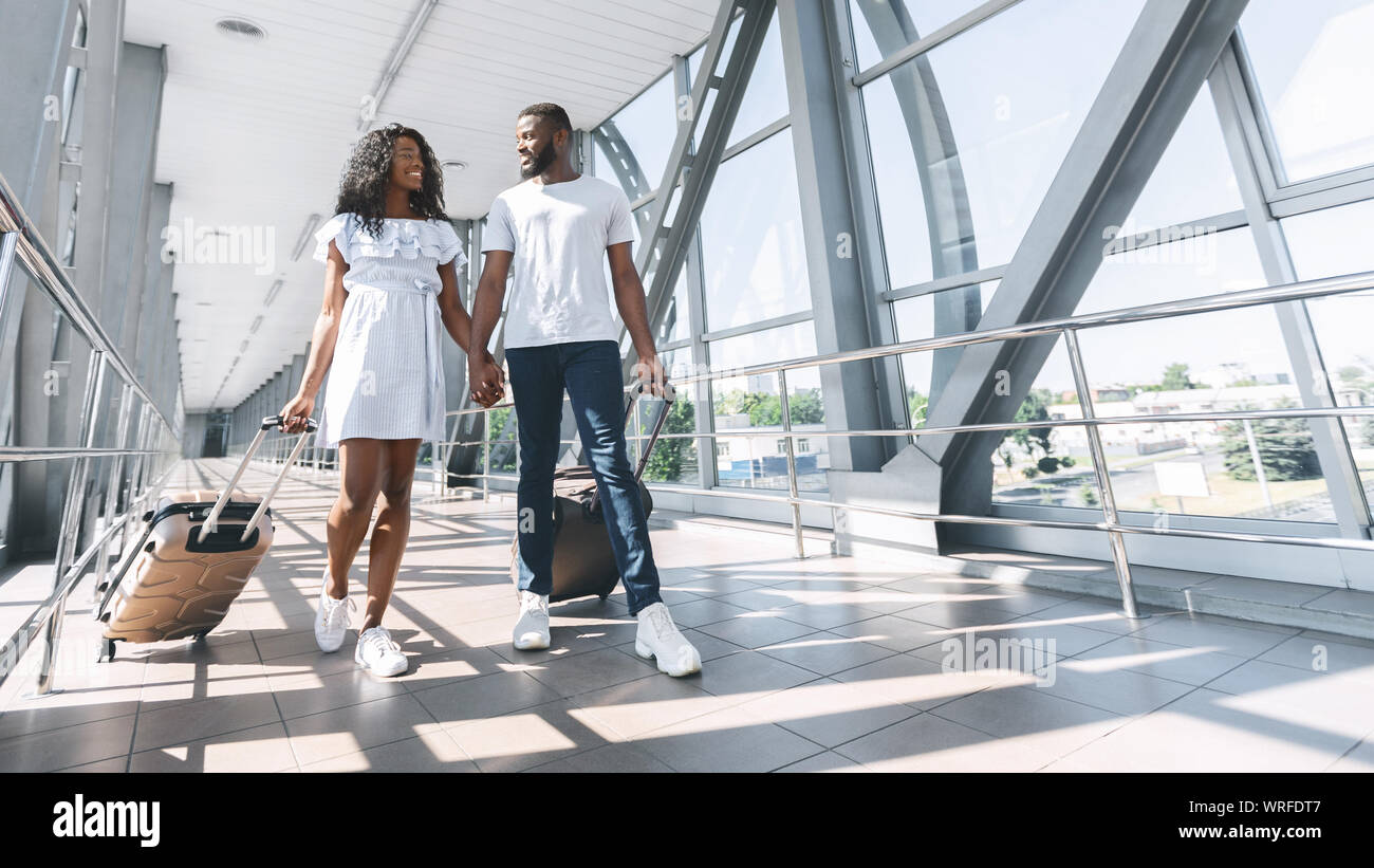 Black couple in love walking with suitcases at airport Stock Photo - Alamy