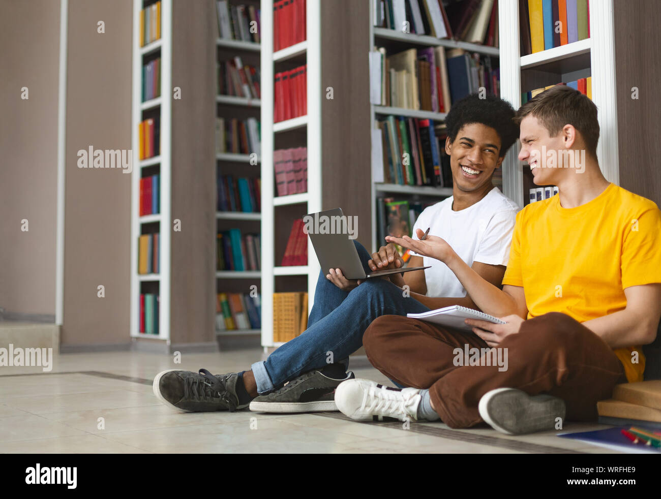 Two young guys having fun while studying at library Stock Photo