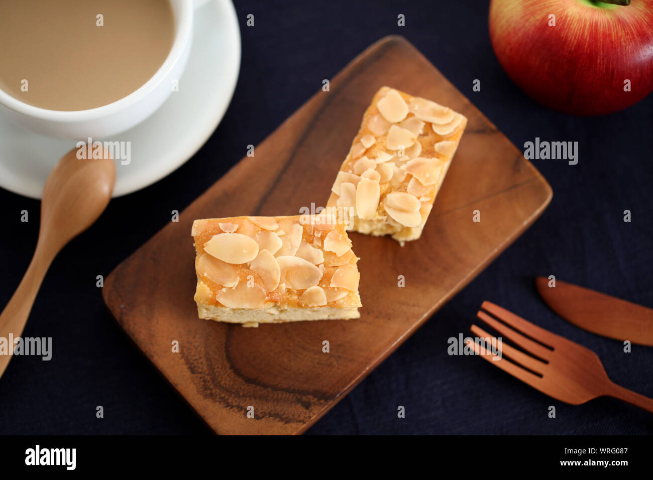 piece of Almond Apple Pound Cake isolated on cutting board and milk coffee on wood table Stock Photo