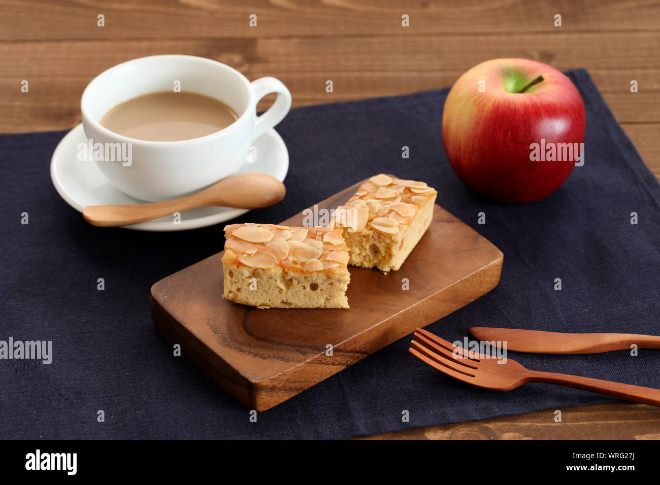 piece of Almond Apple Pound Cake isolated on cutting board and milk coffee on wood table Stock Photo