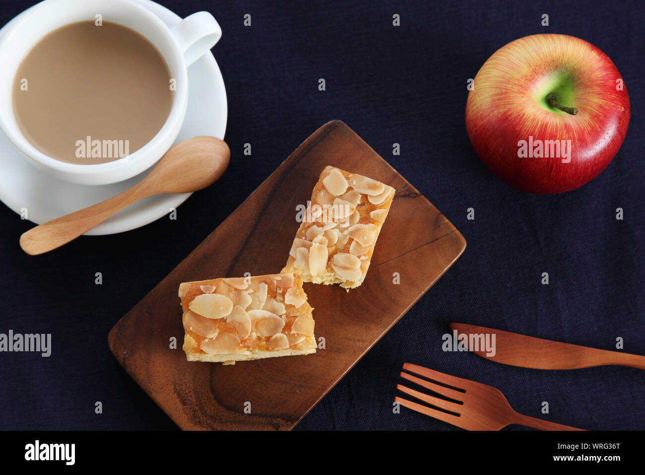 piece of Almond Apple Pound Cake isolated on cutting board and milk coffee on wood table Stock Photo