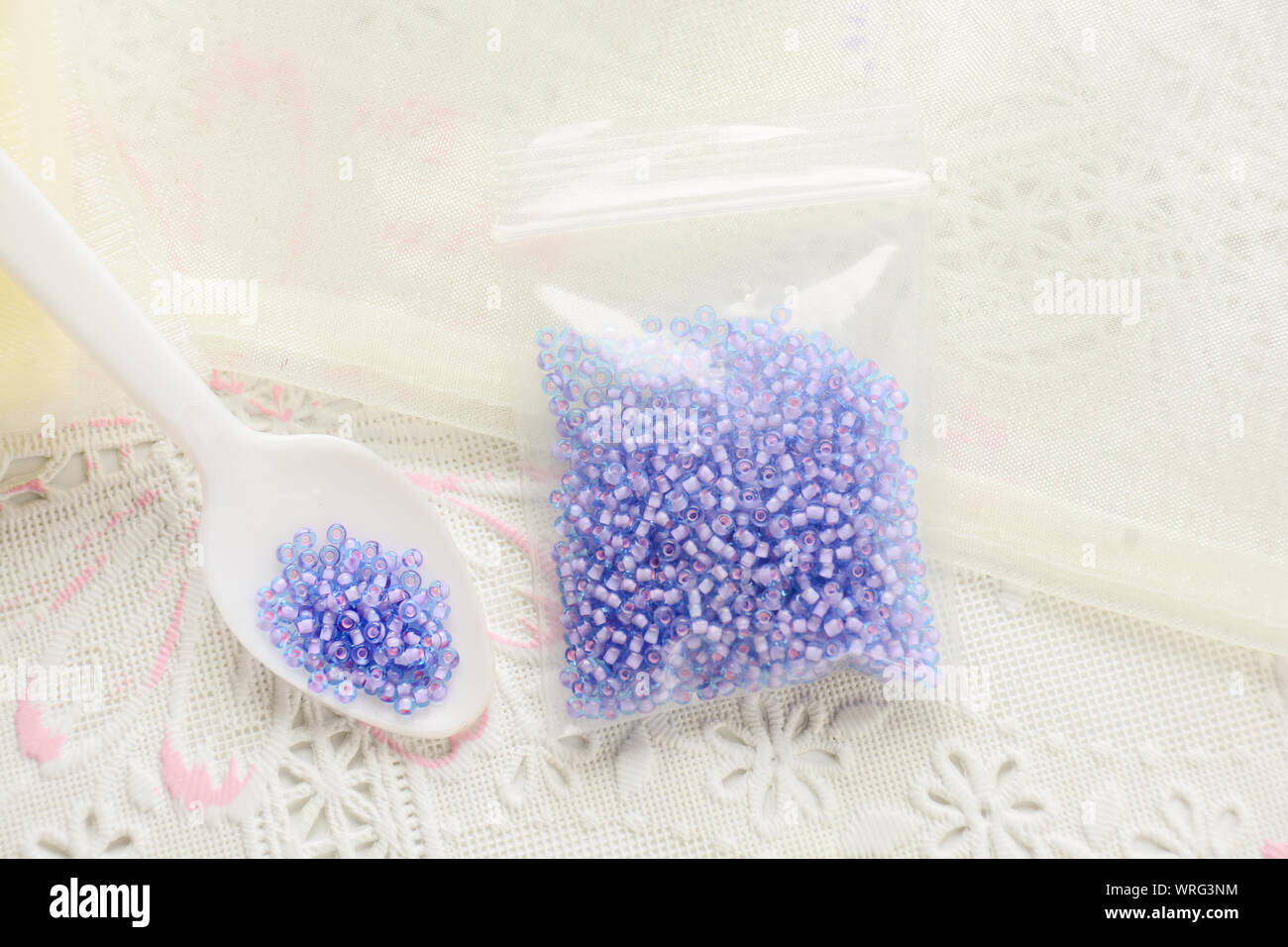 Colorful beads on white fabric surface. Various of shapes and colors to make jewelry Stock Photo