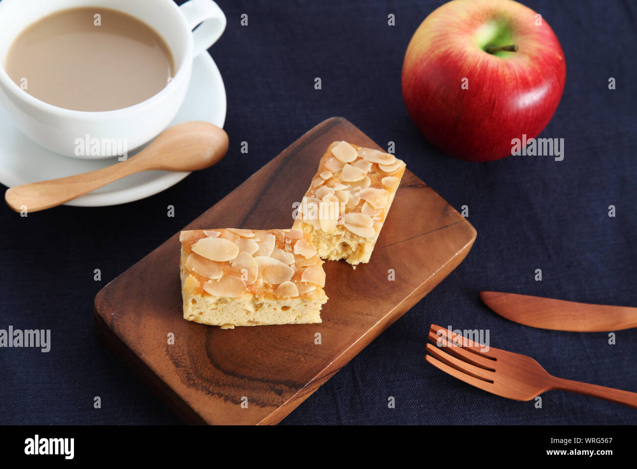 piece of Almond Apple Pound Cake isolated on cutting board and milk coffee on wood table Stock Photo