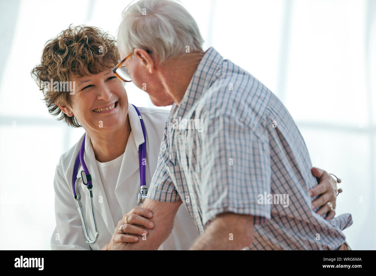Caring female doctor speaking with an elderly male patient Stock Photo ...