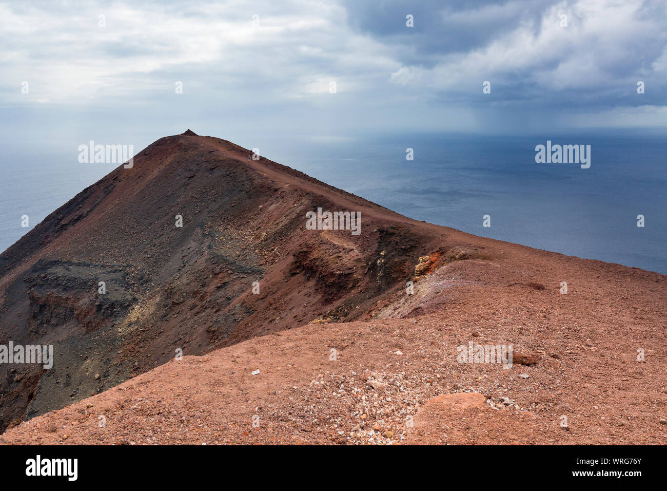 Peak of the colorful crater of the volcano Teneguia in the south of La Palma above the sea. Stock Photo