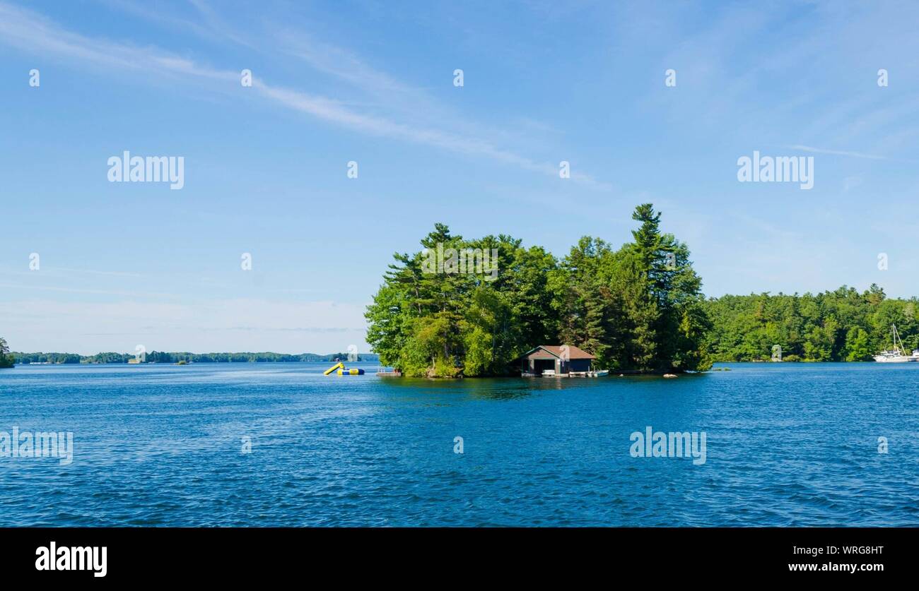 Boathouse Amidst Trees In Ontario Lake Against Sky At Thousand Islands National Park Stock Photo