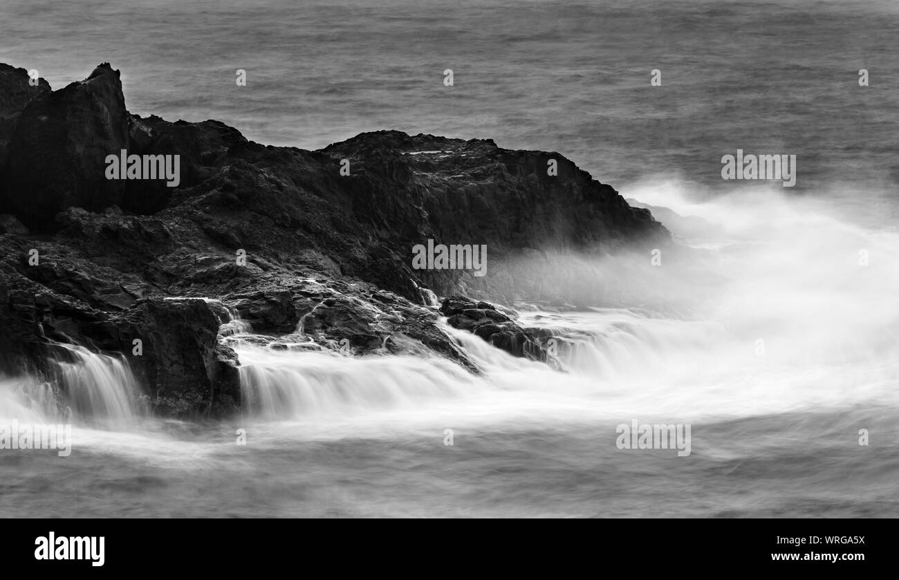 Long exposure detail view of tall splashing waves hitting the rocks with tiny waterfalls at Playa de Nogales in La Palma, Spain. Stock Photo