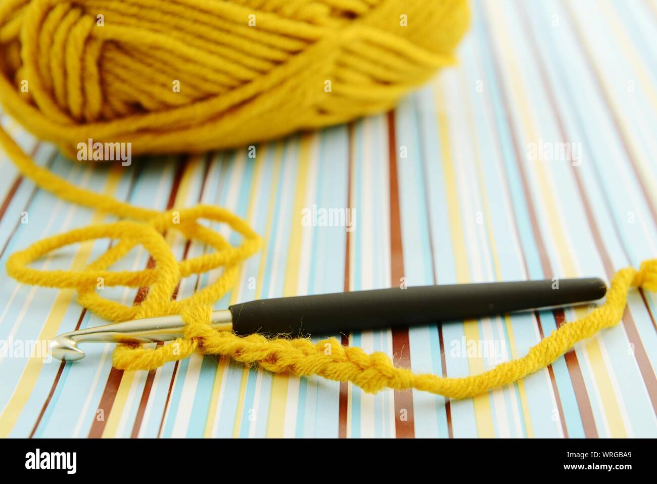 Ball Of Wool With Crochet Hook On Striped Paper Stock Photo