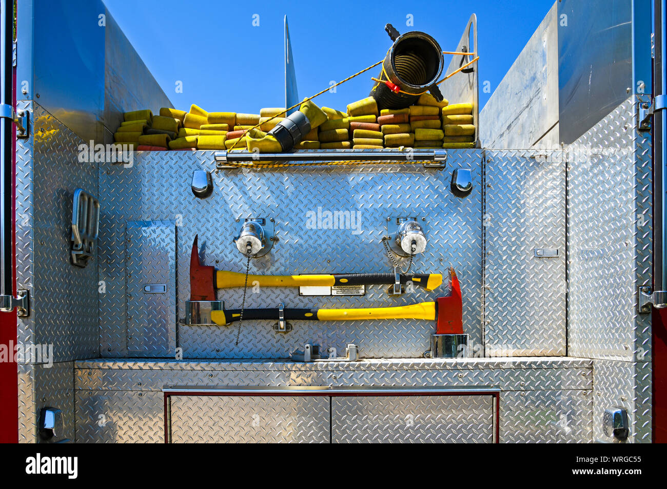 Close-up Image of the Rear of a Fire Truck with Fire Hose and Emergency Axes Stock Photo