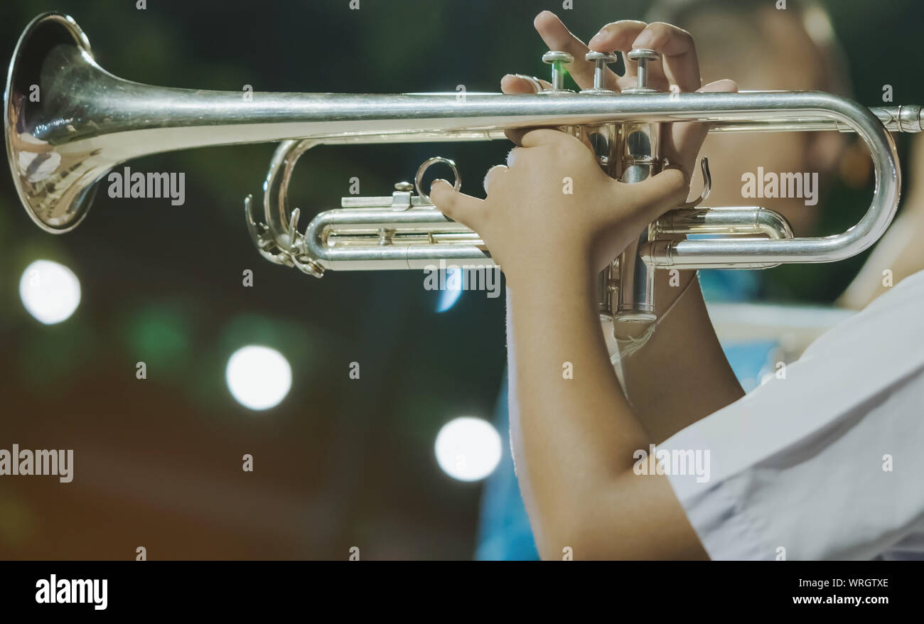 Male student with friends blow the trumpet with the band for performance on stage at night Stock