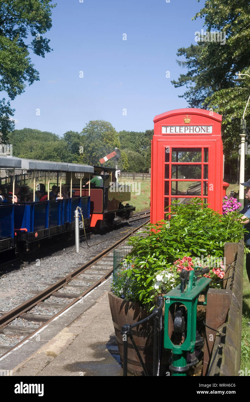 steam train ready to depart at station in Whipsnade zoo with old red telephone box and flower bed across the platform from the train Stock Photo