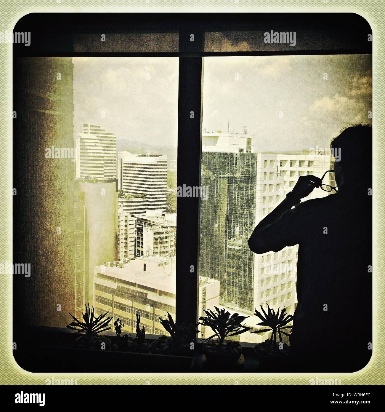 Silhouette man looking through window hires stock photography and