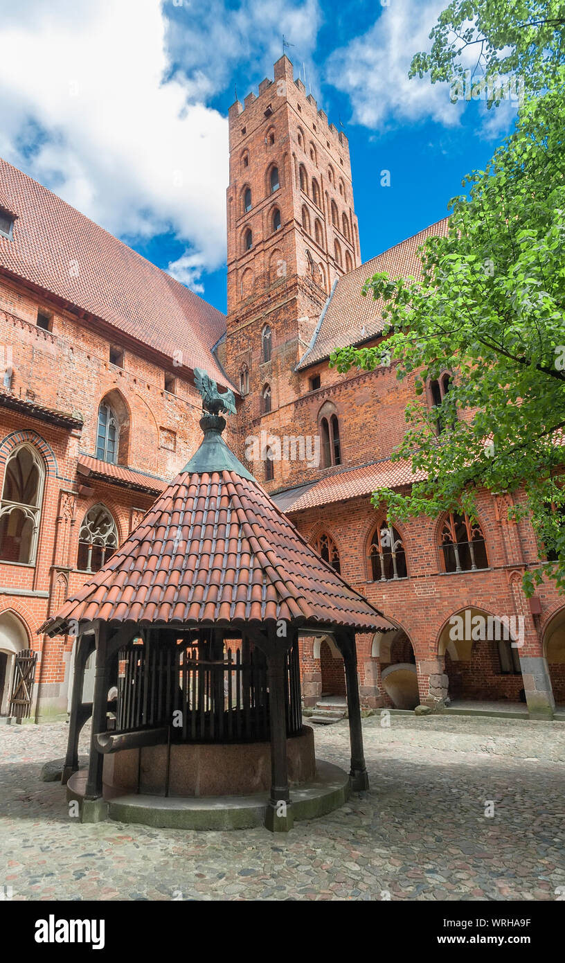 The inner courtyard with a well and a tall tower Malbork castle. Marienburg. Poland Stock Photo