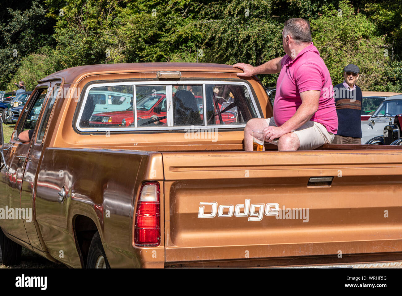 Man with beer glass riding in back of a Dodge pickup truck, at a classic car show, Hinton Arms, Cheriton, Hampshire, UK Stock Photo