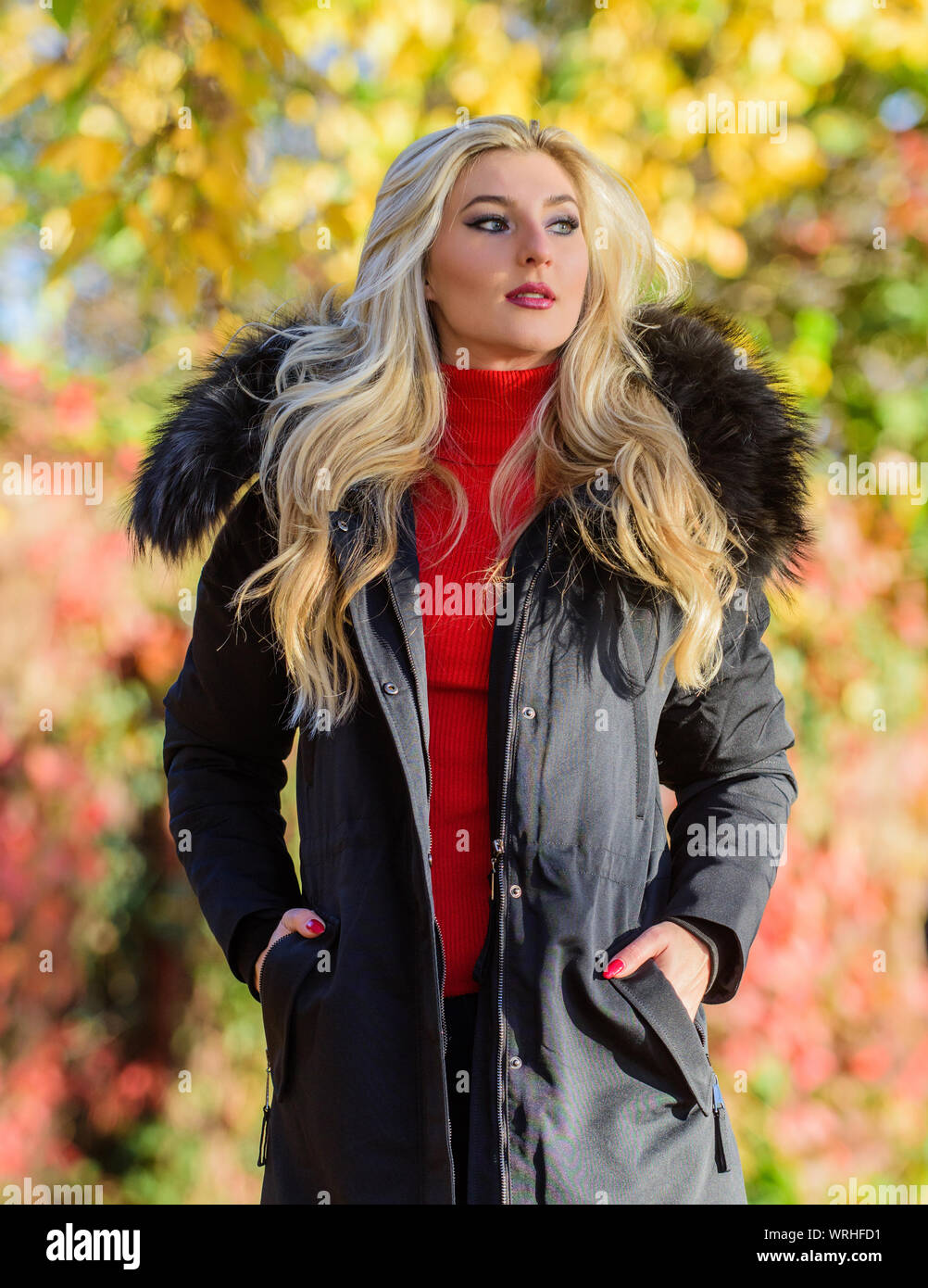 Woman long blonde hair wear stylish outfit with parka. Modern outfit for  youth. Girl in warm coat stand in park nature background defocused. Create  fall outfit to feel comfortable and pretty Stock