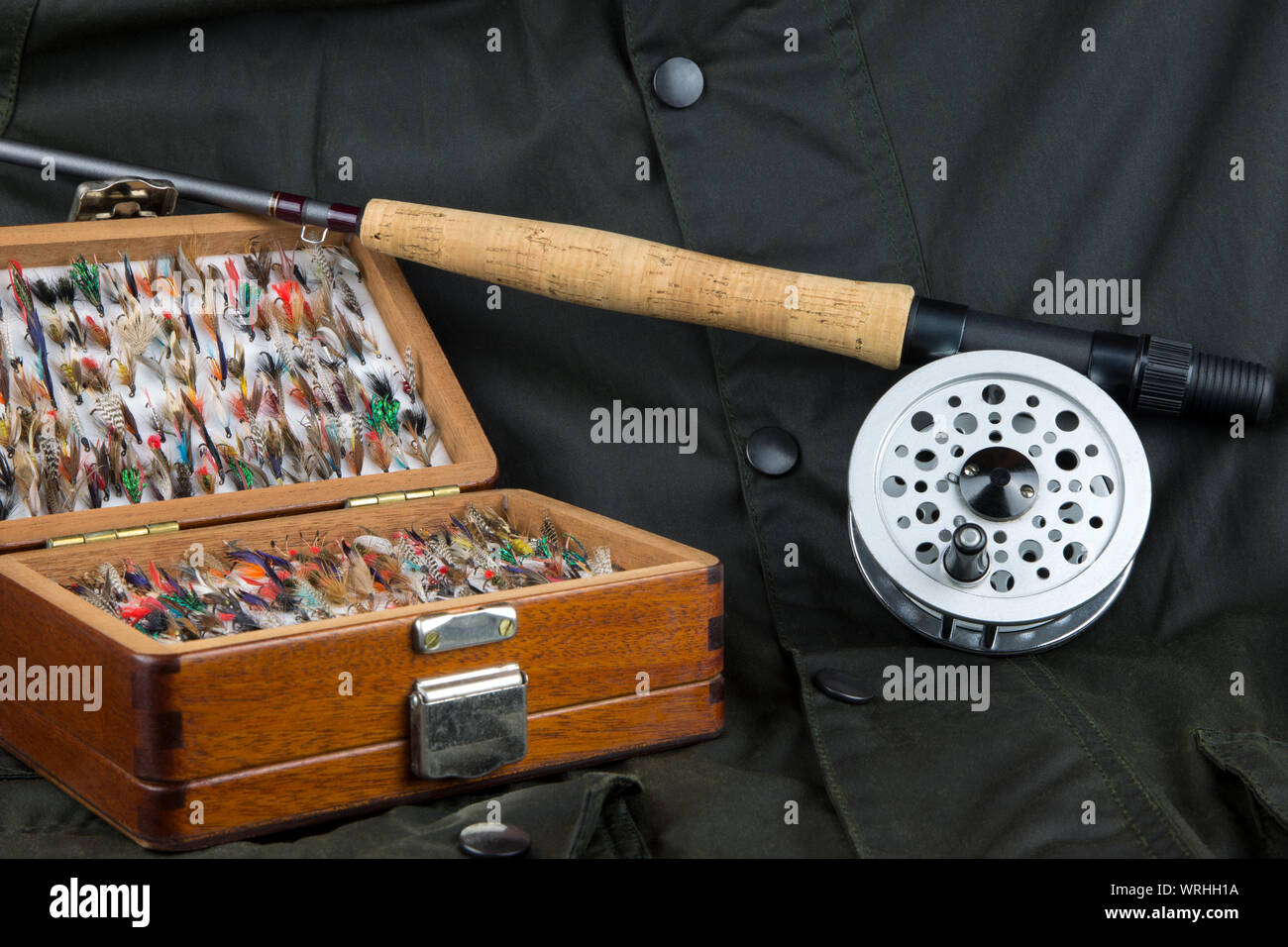 Fly fishing rod reel and flies on outdoor coat background Stock Photo