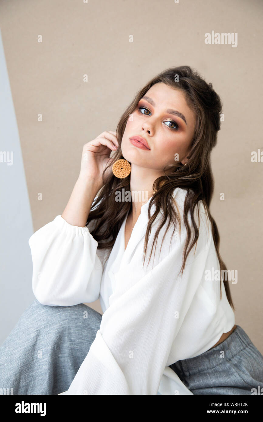 Portrait of thoughtful brunette model in white blouse demonstrating ear-rings Stock Photo