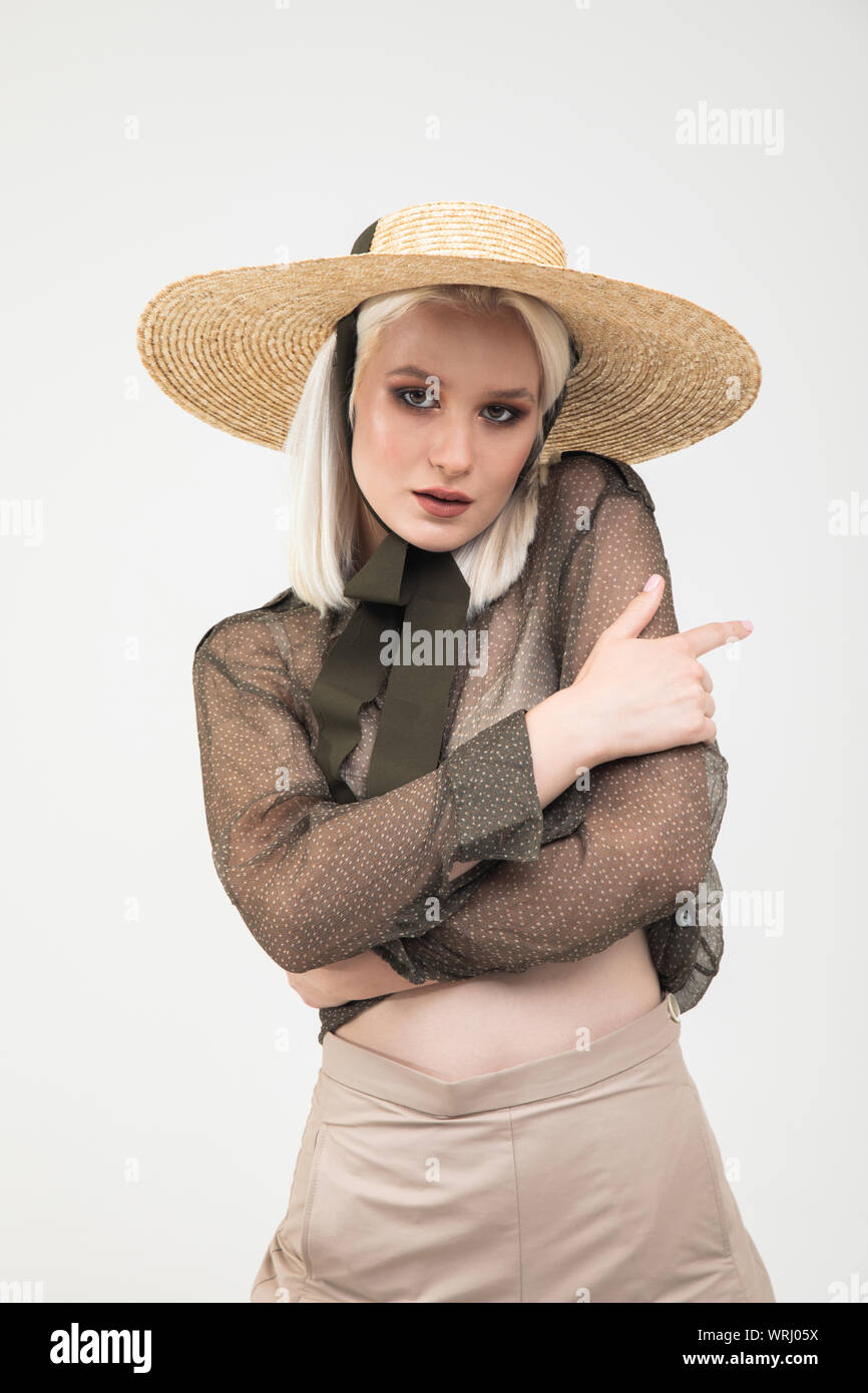 Portrait of sensual blonde girl in transparent blouse hugging herself isolated white background Stock Photo