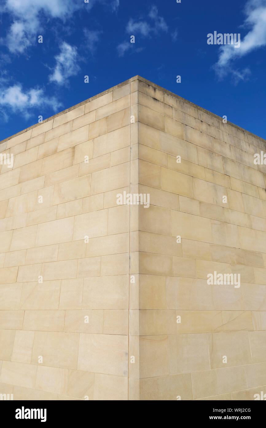 The corner detail of a stone building from a different perspective featuring Ashlar masonry set against a blue sky. Stock Photo