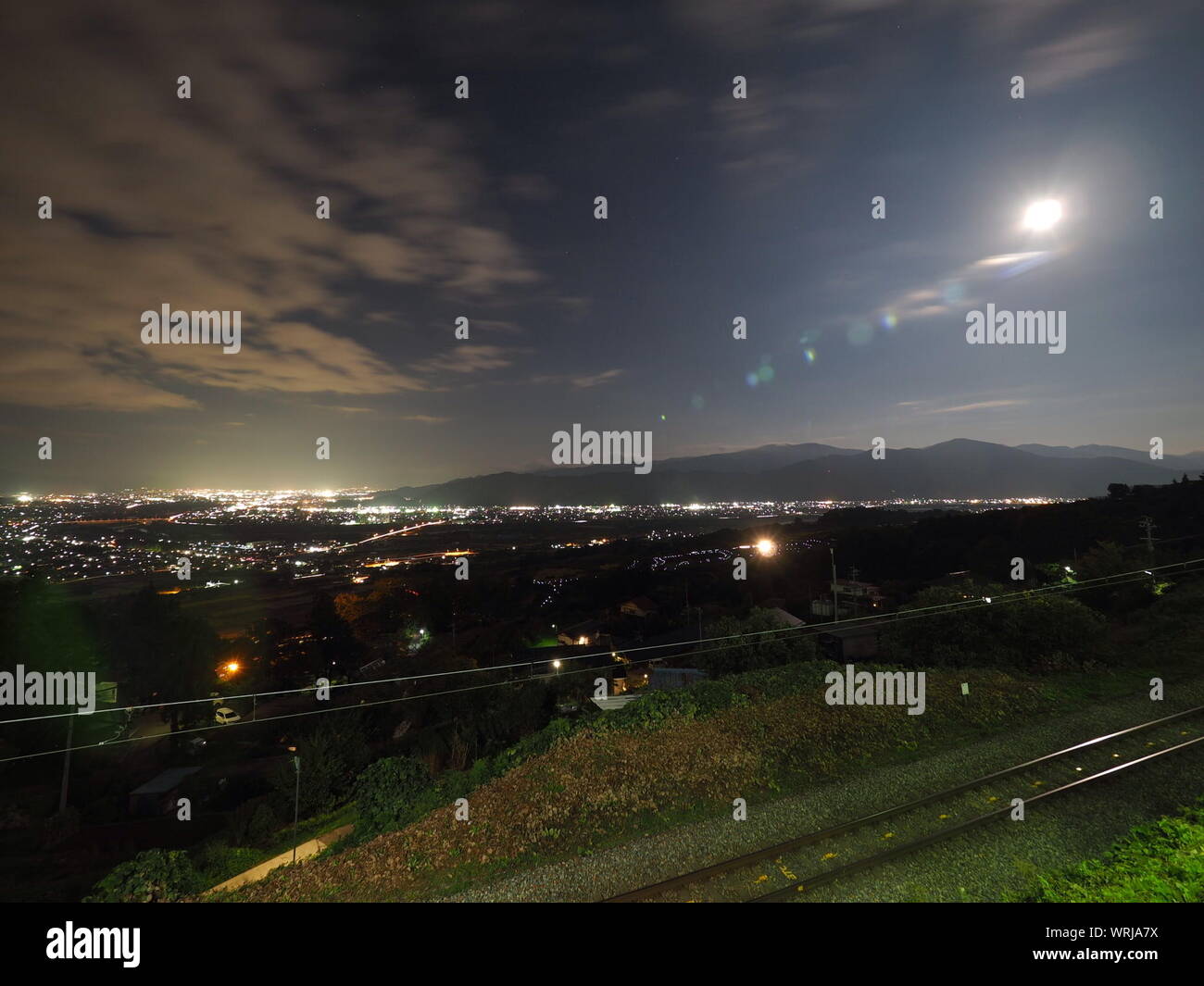 Scenic View Of Illuminated City With Railroad Tracks Against Sky Stock Photo